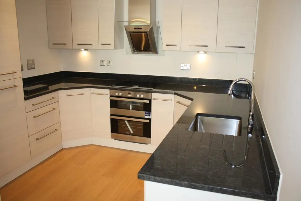 Cocina con encimera oscura y armarios blancos